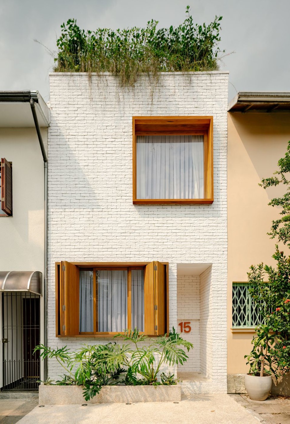 Na fachada da casa, o tijolinho branco aparente, da Pedra Paulista, foi combinada aos caixilhos em madeira freijó, da Madeira Art — Foto: Fran Parente/Divulgação | Projeto do escritório Rua 141 Arquitetura