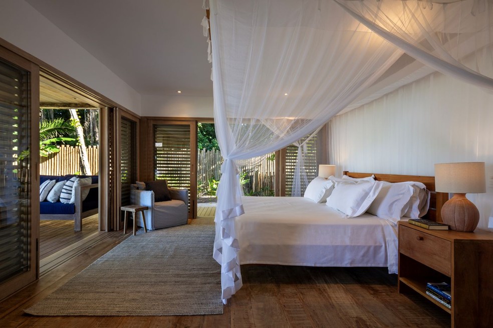 QUARTO | A cama e as mesas laterais foram desenhadas pelo escritório, acompanhadas por abajures de cerâmica de Gabriel Calazans. Poltrona da Casa do Lírio. Tapete da Haith. O mosquiteiro, da Marta Stampelle, reforça a atmosfera leve e acolhedora — Foto: Antonio Soto/Divulgação