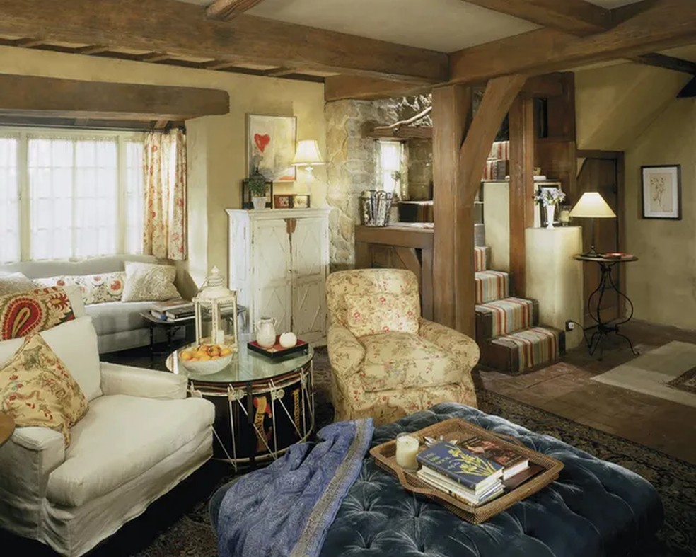 Os interiores do Rosehill Cottage combinam vigas de madeira aparentes, lareiras e tecidos estampados. A direção de Nancy Meyers deu destaque à casa, que se tornou um dos cenários mais lembrados da comédia romântica — Foto: Columbia Pictures/Divulgação