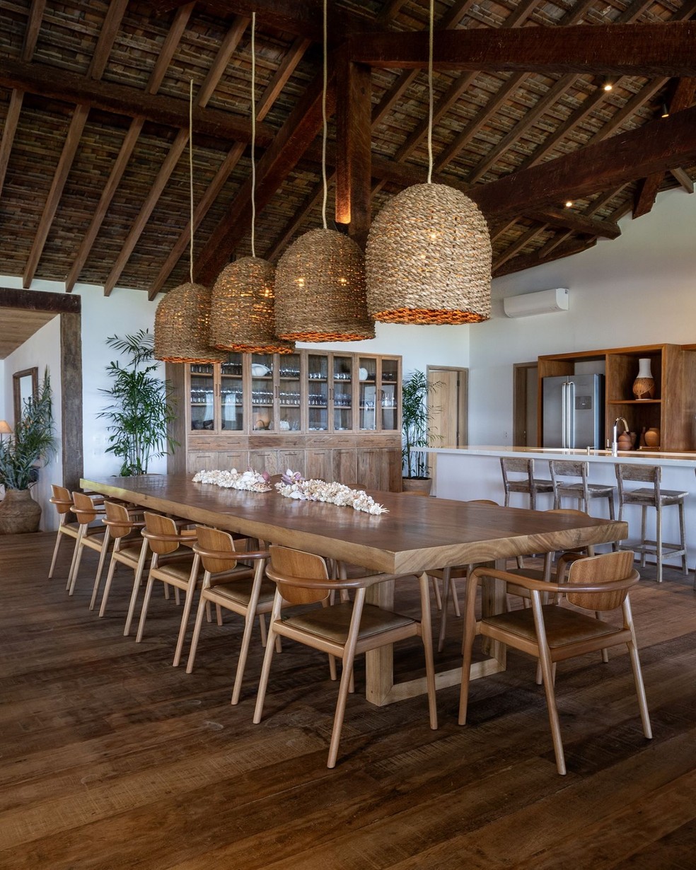SALA DE JANTAR | A mesa de madeira desenhada pelo escritório é acompanhada por cadeiras da Breton. As luminárias pendentes de fibras naturais, da loja Cipó da Mata, em Trancoso, reforçam a atmosfera praiana. A cristaleira, também com desenho autoral e executada pela Marcenaria Abraão, organiza louças e objetos — Foto: Antonio Soto/Divulgação