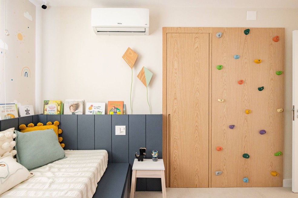 QUARTO INFANTIL | A bicama do tipo tatame em MDF Lord, da Arauco, acompanha o painel de marcenaria em lâmina de carvalho-americano, que incorpora uma parede de escalada. A pintura artística feita à mão, da Art da Lari, acrescenta um toque lúdico ao ambiente — Foto: Pedro Mello/Interior da Foto/Divulgação