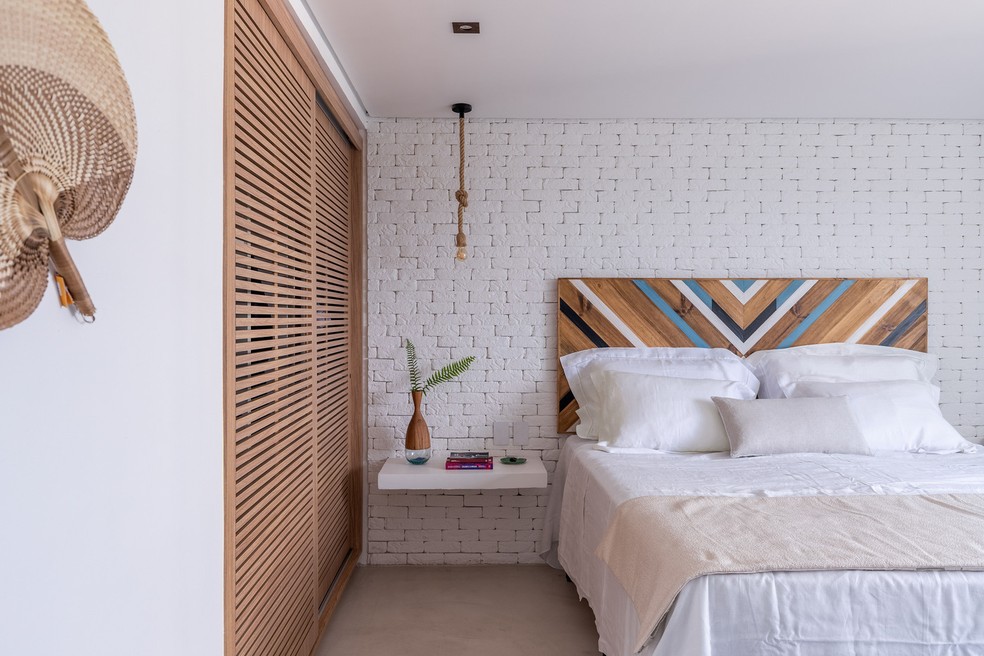 A combinação entre tijolinho branco e madeira natural é uma das alternativas para criar ambientes mais acolhedores. No quarto, a cabeceira colorida levanta a composição — Foto: Rafael Renzo/Divulgação | Projeto dos arquitetos Aiê Tombolato e Livia Salem