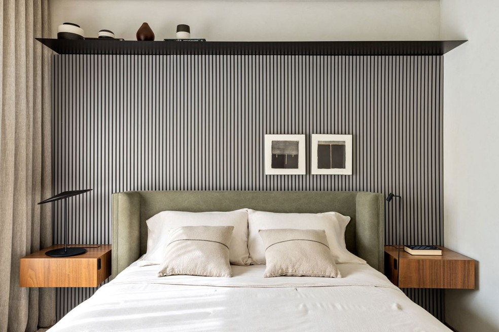 Antes de escolher a cabeceira, é importante considerar as dimensões da cama, do colchão e a proporção em relação ao ambiente. O ambiente segue a materialidade do apartamento, com painel ripado de laca cinza, que destaca a cabeceira estofada verde — Foto: Fran Parente/Divulgação | Projeto das arquitetas Flávia Romi e Marina Menossi